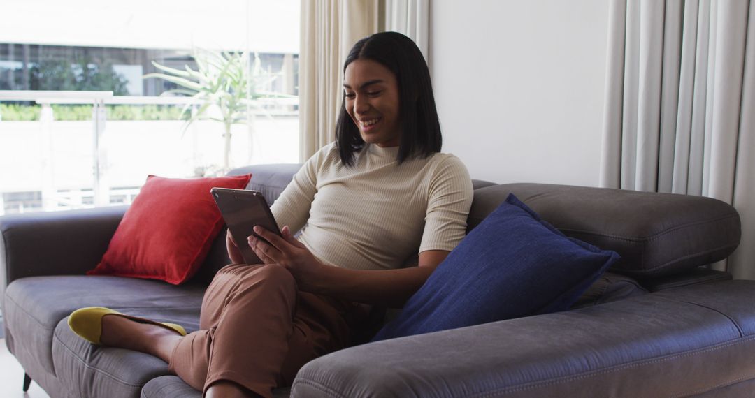 Woman Relaxing on Sofa Reading Tablet in Modern Living Room - Free Images, Stock Photos and Pictures on Pikwizard.com