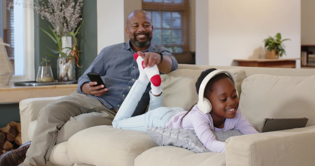 Father and Daughter Bonding on Sofa with Gadgets