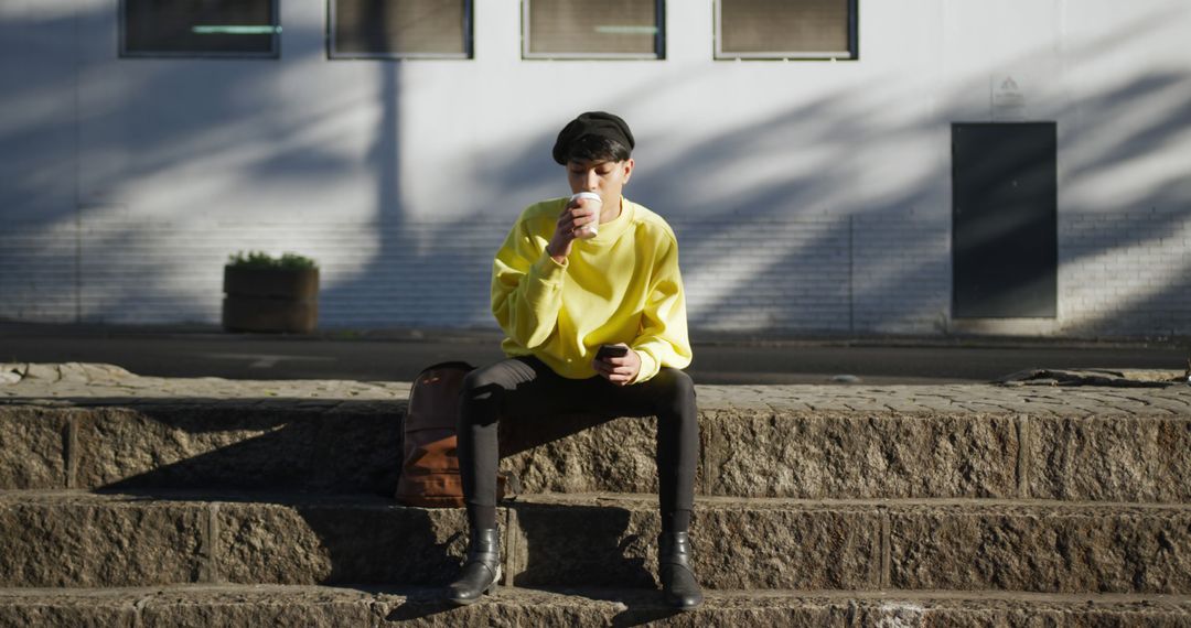 Trendy Young Man Sitting on Stone Steps Drinking Coffee - Free Images, Stock Photos and Pictures on Pikwizard.com