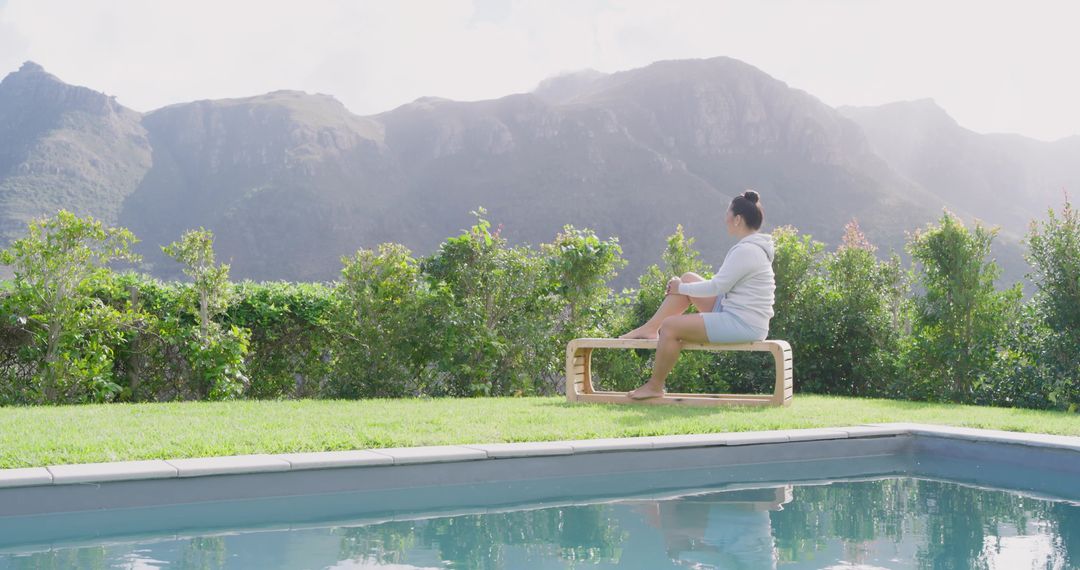 Asian Woman Relaxing by Poolside with Mountain View in Serene Backyard