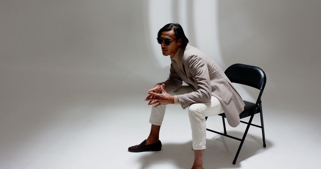 Man in Beige Blazer Sitting on Folding Chair in Modern Studio