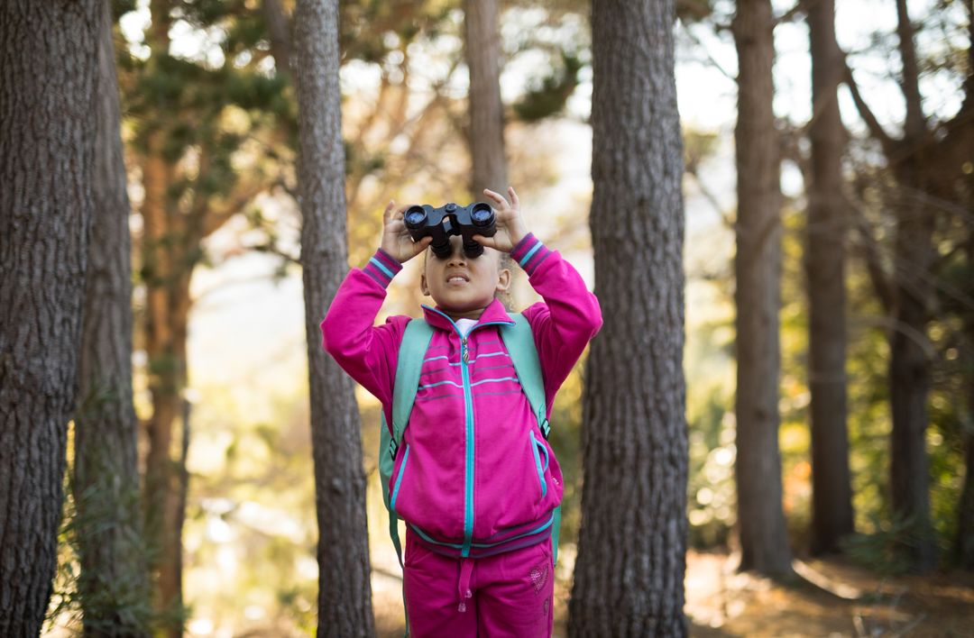 Young Explorer Scanning the Treetops with Binoculars in Pine Forest