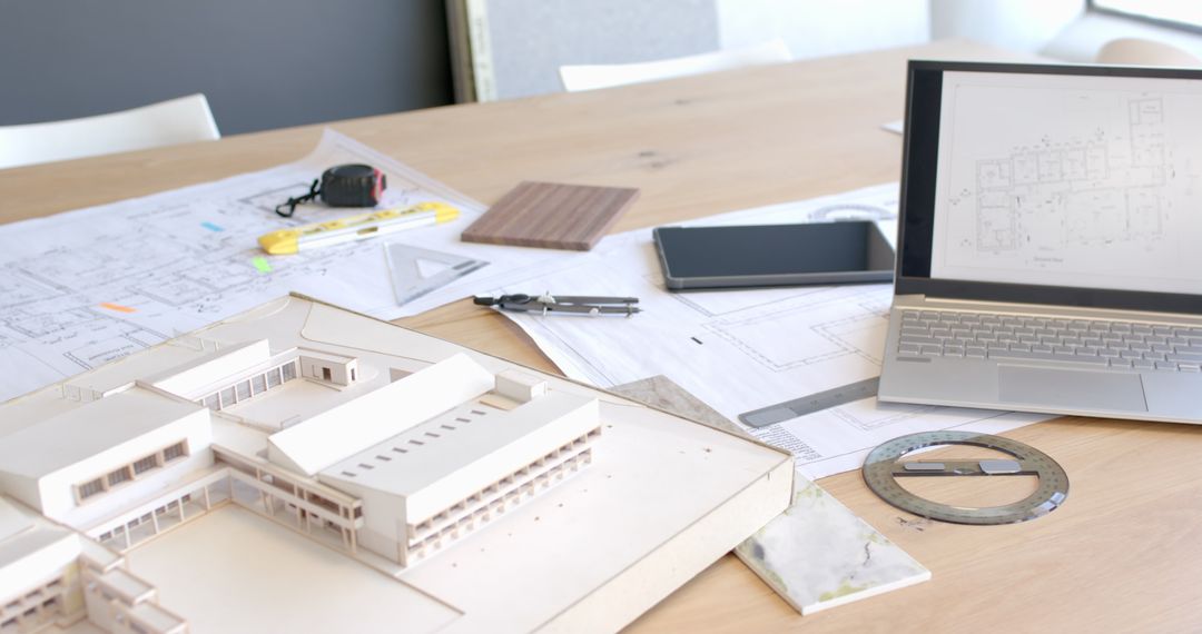 Architectural Model with Blueprints and Gadgets on Workspace Table