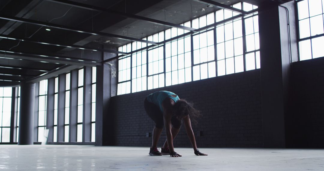 Woman Stretching in Spacious Industrial Room with Large Windows - Free Images, Stock Photos and Pictures on Pikwizard.com