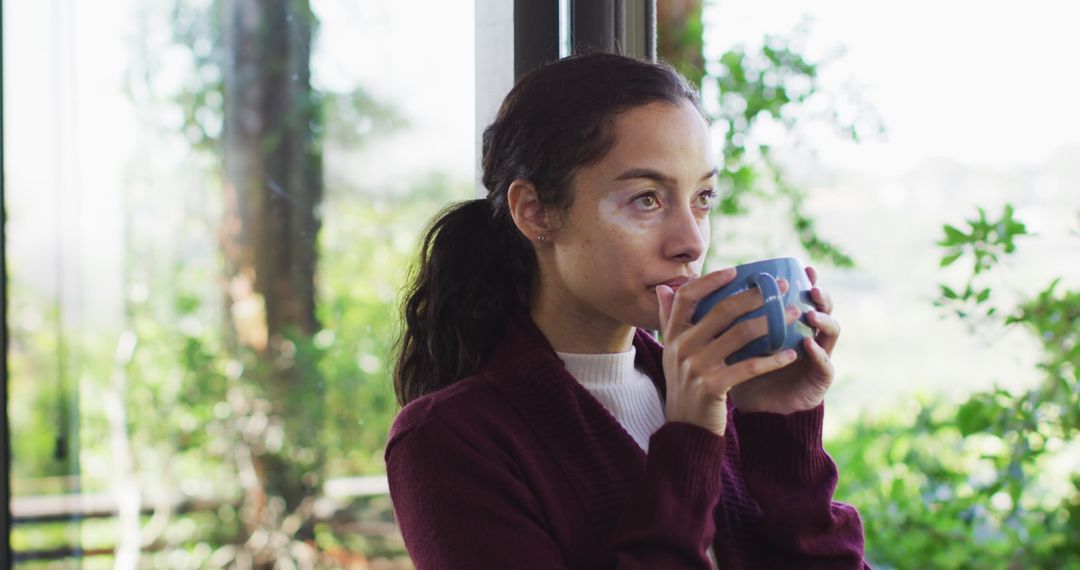 Pensive Woman Enjoying Hot Beverage by Large Window