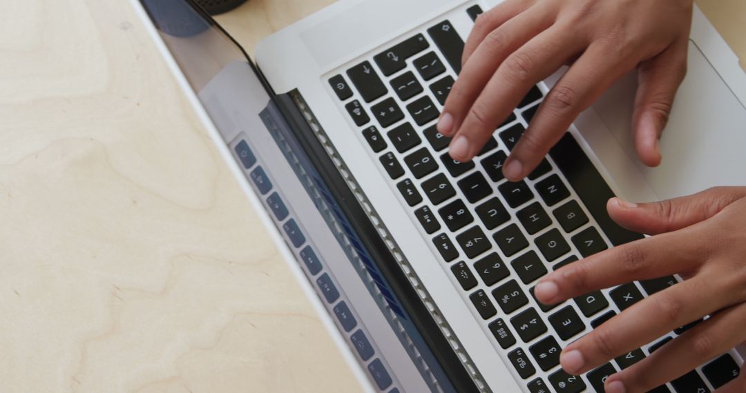 Close-Up Hands Typing on Laptop Keyboard at Wooden Desk