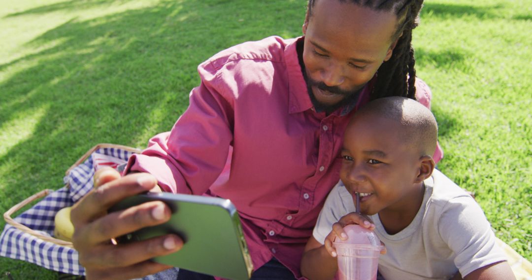 Image of happy african american father and son having picnic outdoors and taking selfie - Free Images, Stock Photos and Pictures on Pikwizard.com