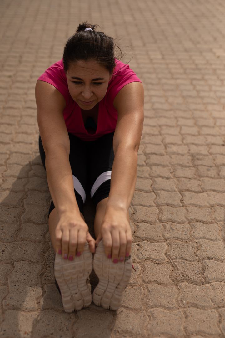 Biracial Woman Stretching Legs During Outdoor Boot Camp Training - Free Images, Stock Photos and Pictures on Pikwizard.com