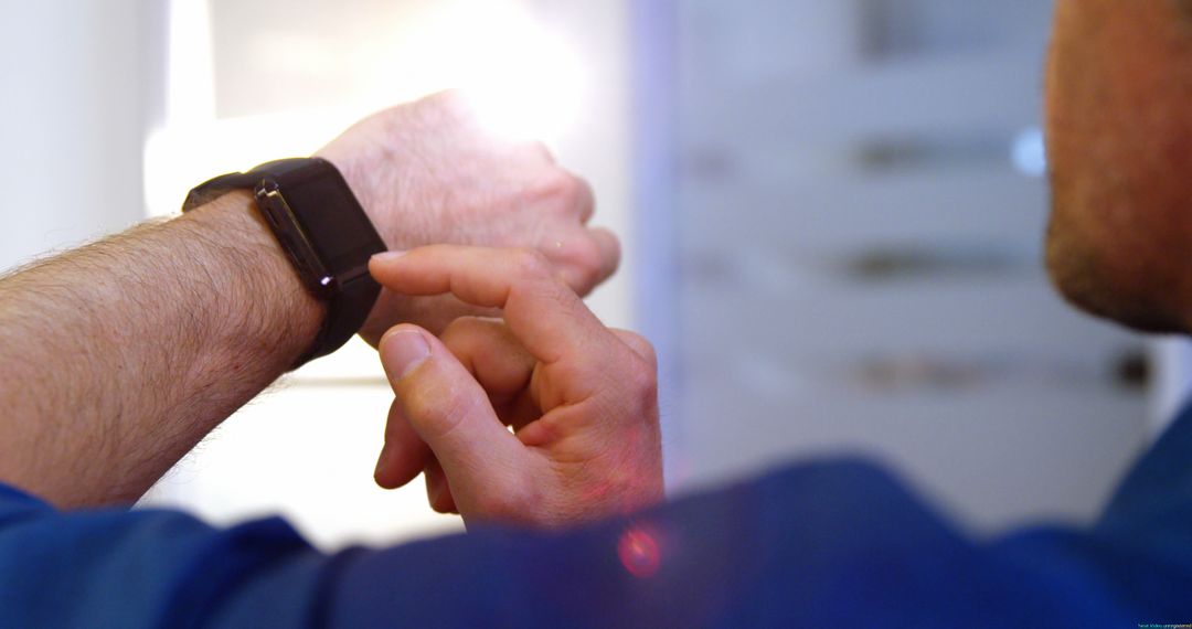 Man Using Smartwatch in Modern Office Setting - Free Images, Stock Photos and Pictures on Pikwizard.com