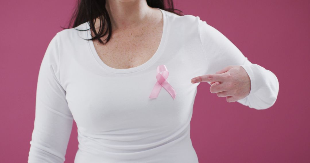 Woman Pointing at Pink Breast Cancer Awareness Ribbon on White Shirt - Free Images, Stock Photos and Pictures on Pikwizard.com