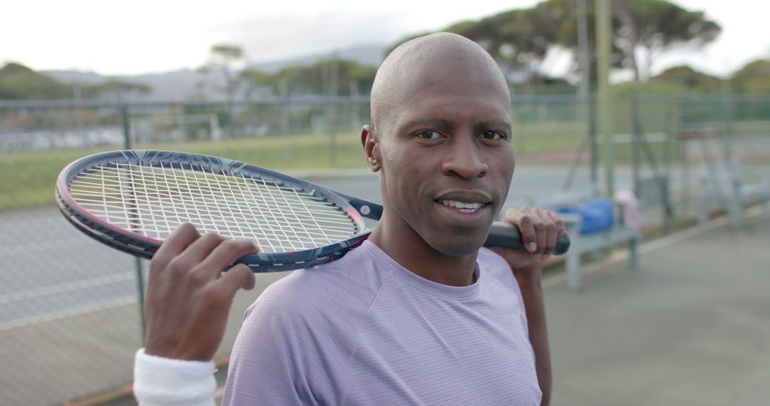 Confident African American Male Tennis Player Holding Racket on Court - Free Images, Stock Photos and Pictures on Pikwizard.com