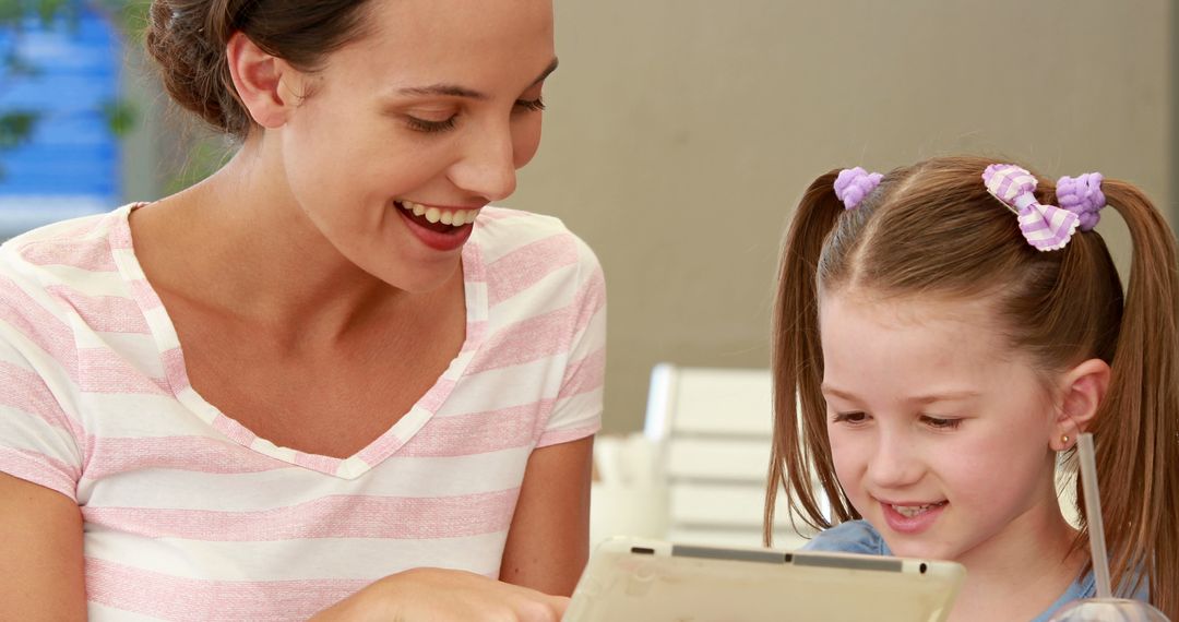 Mother and Daughter Using Tablet Together Smiling Indoors - Free Images, Stock Photos and Pictures on Pikwizard.com