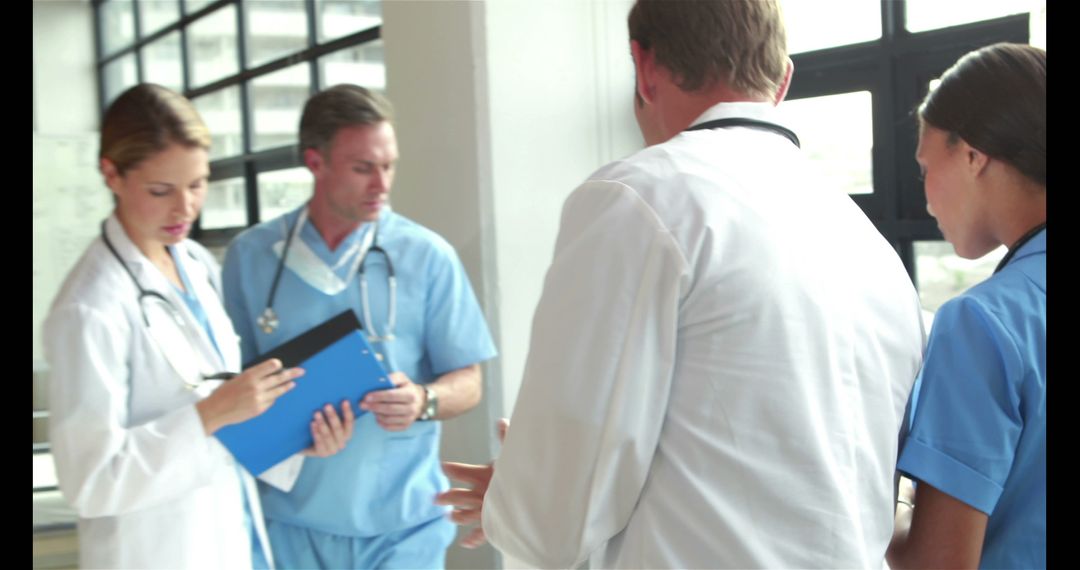 Medical Team Discussing Patient Treatment in Hospital Hallway - Free Images, Stock Photos and Pictures on Pikwizard.com