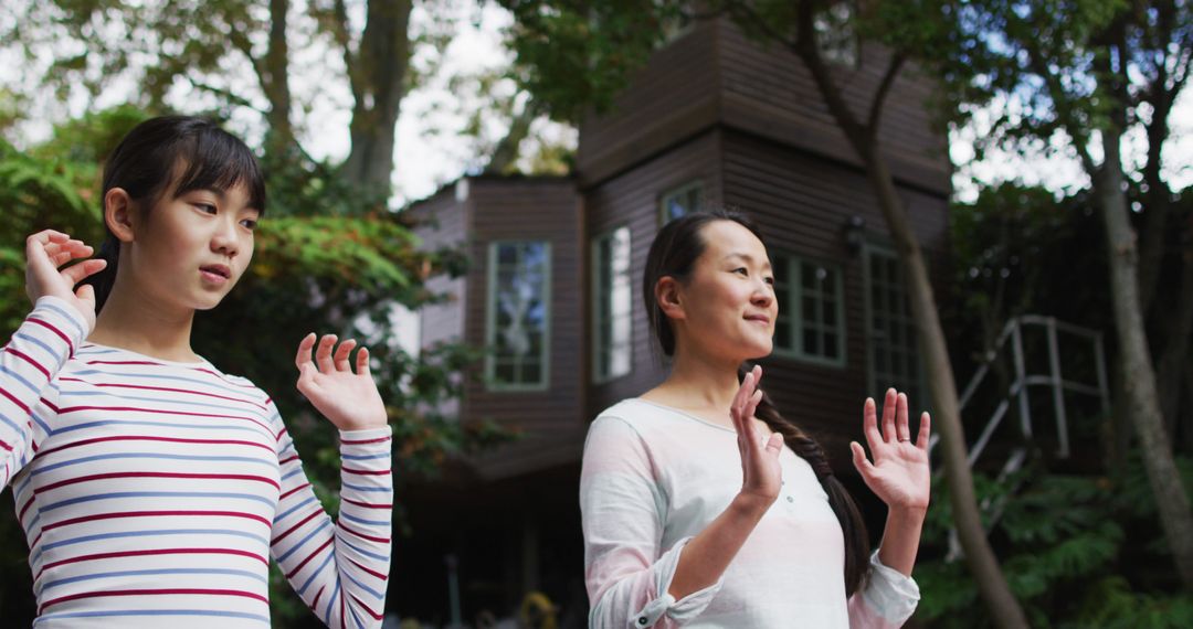 Asian Mother and Daughter Practicing Tai Chi in Garden - Free Images, Stock Photos and Pictures on Pikwizard.com