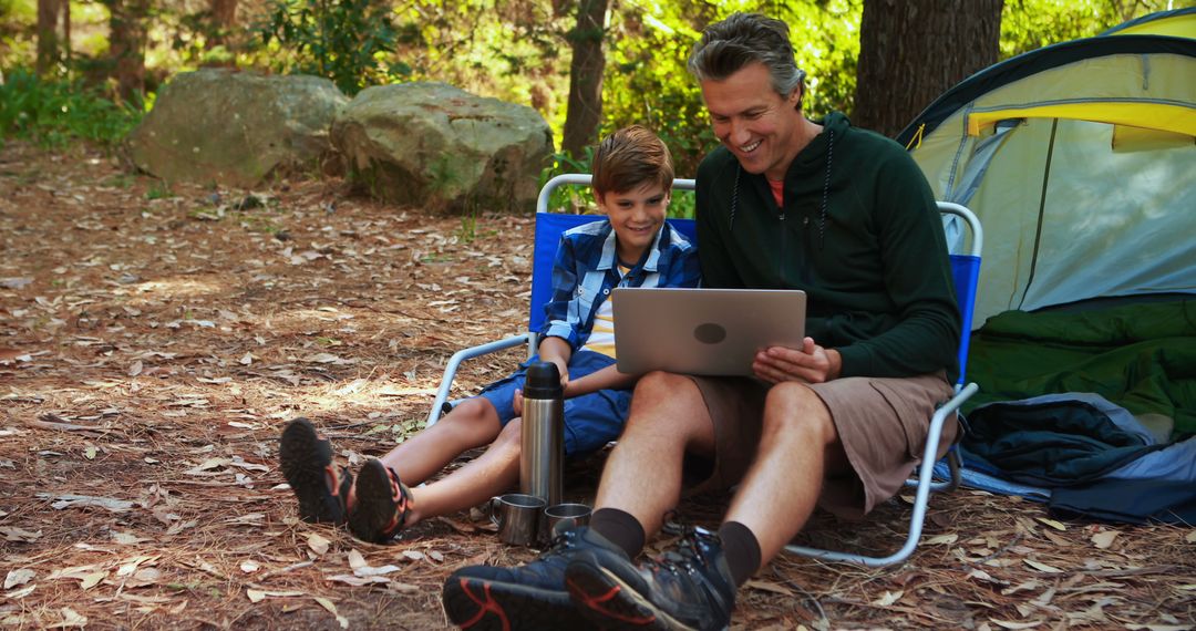 Father and Son Camping Using Laptop in Forest - Free Images, Stock Photos and Pictures on Pikwizard.com