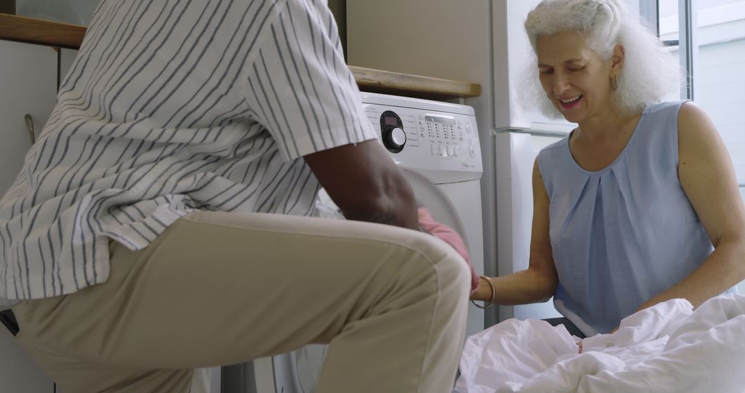 Senior Couple Working Together Loading Washing Machine