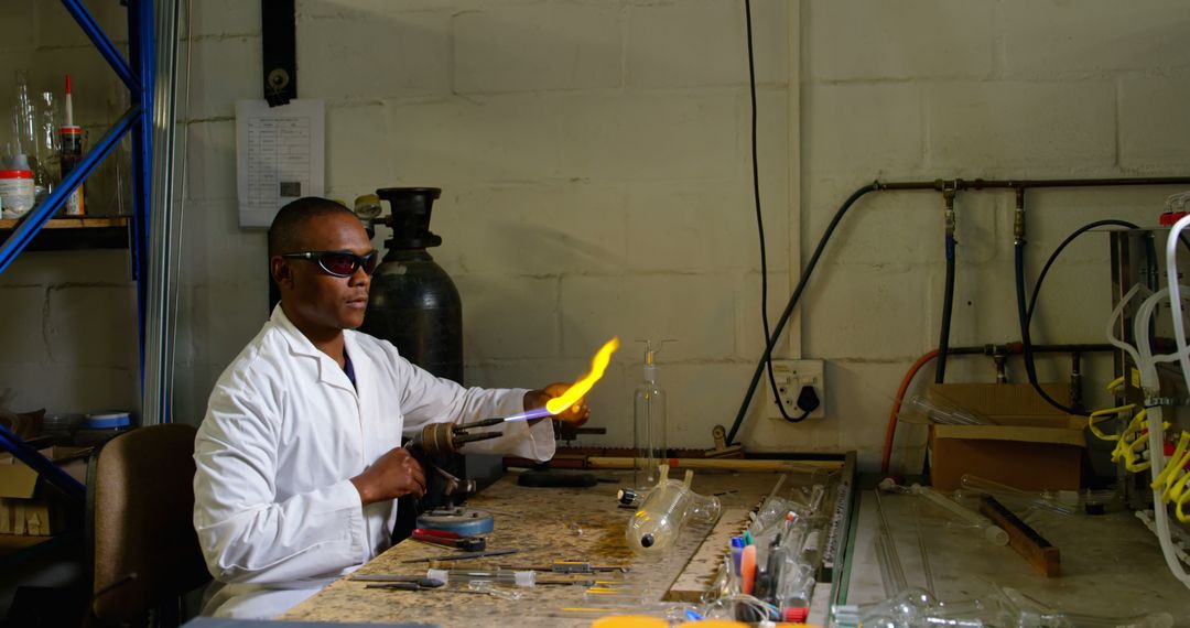 Side view of black male worker blowing glass in glass factory - Free Images, Stock Photos and Pictures on Pikwizard.com