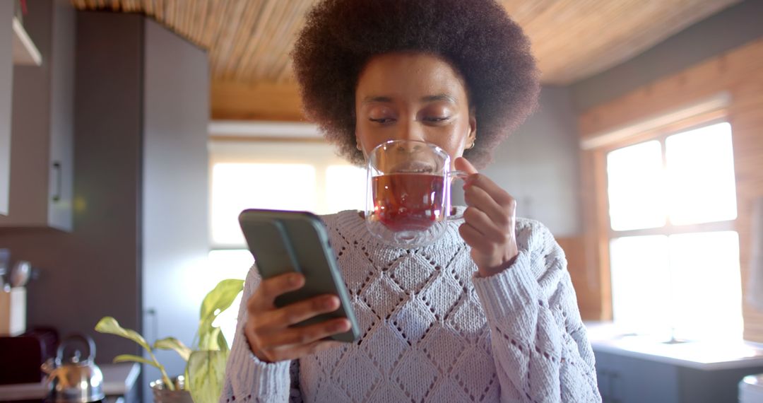 Young Woman Enjoying Hot Beverage while Using Smartphone at Home - Free Images, Stock Photos and Pictures on Pikwizard.com