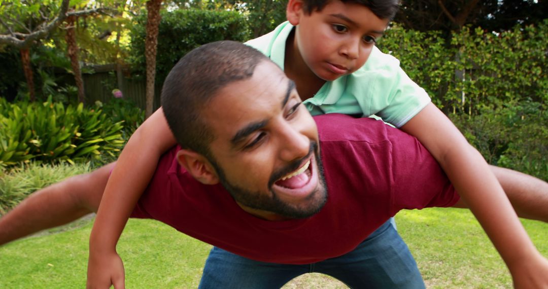 Father and Son Embracing Happy Bond Outdoors in Playful Piggyback Moment - Free Images, Stock Photos and Pictures on Pikwizard.com