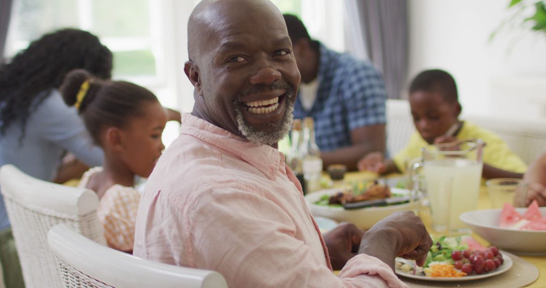 Cheerful man enjoying family meal at dining table indoors - Free Images, Stock Photos and Pictures on Pikwizard.com