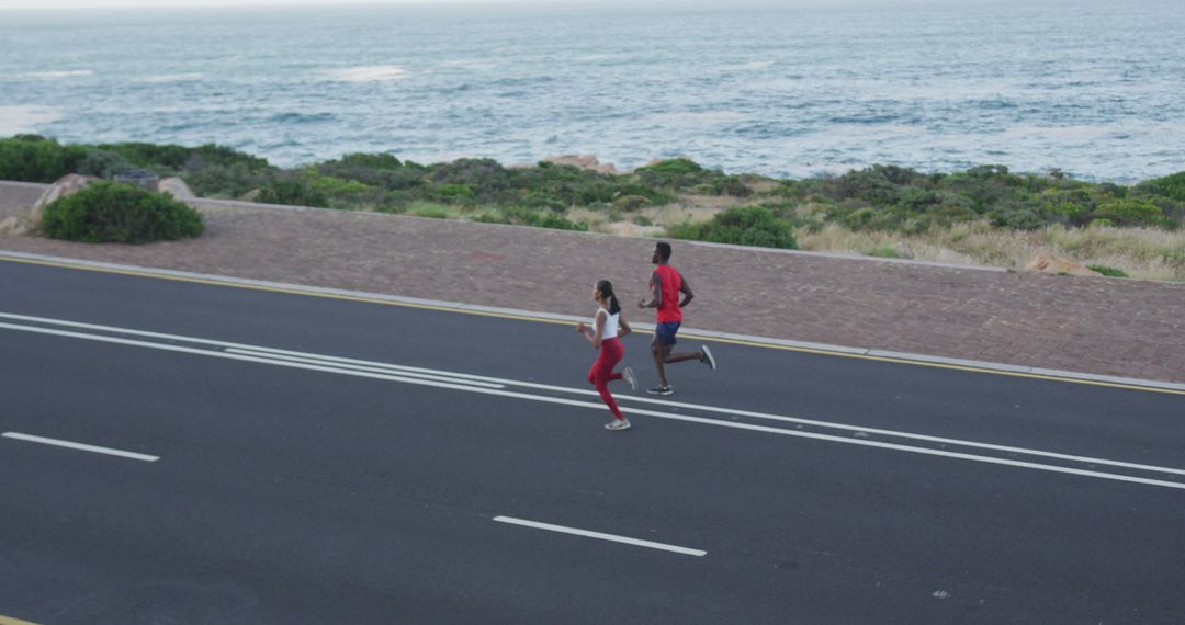 Two Runners Exercising on Coastal Road with Ocean View - Free Images, Stock Photos and Pictures on Pikwizard.com