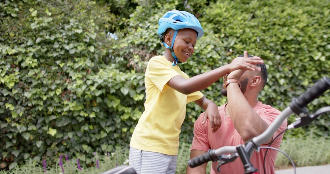 Father and Son Enjoying Cycling Together with High Five in Park