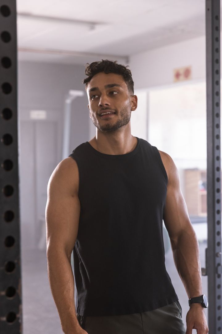 Muscular Athlete Resting in Gym Next to Squat Rack