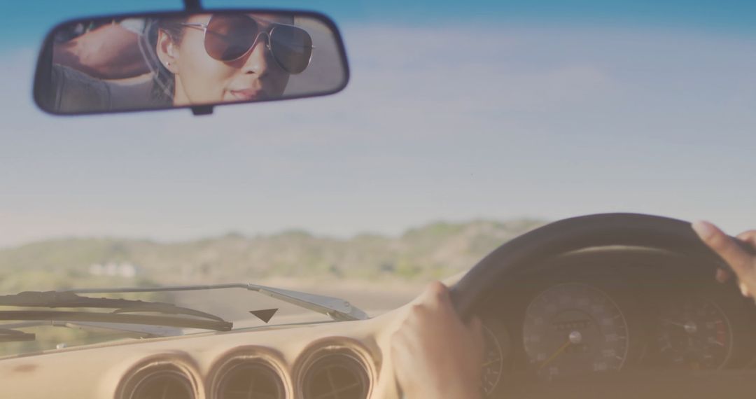 Couple Driving Car with View of Seaside in Rearview Mirror