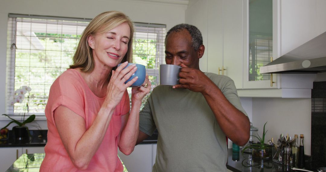 Happy diverse senior couple drinking coffee and talking standing in kitchen - Free Images, Stock Photos and Pictures on Pikwizard.com
