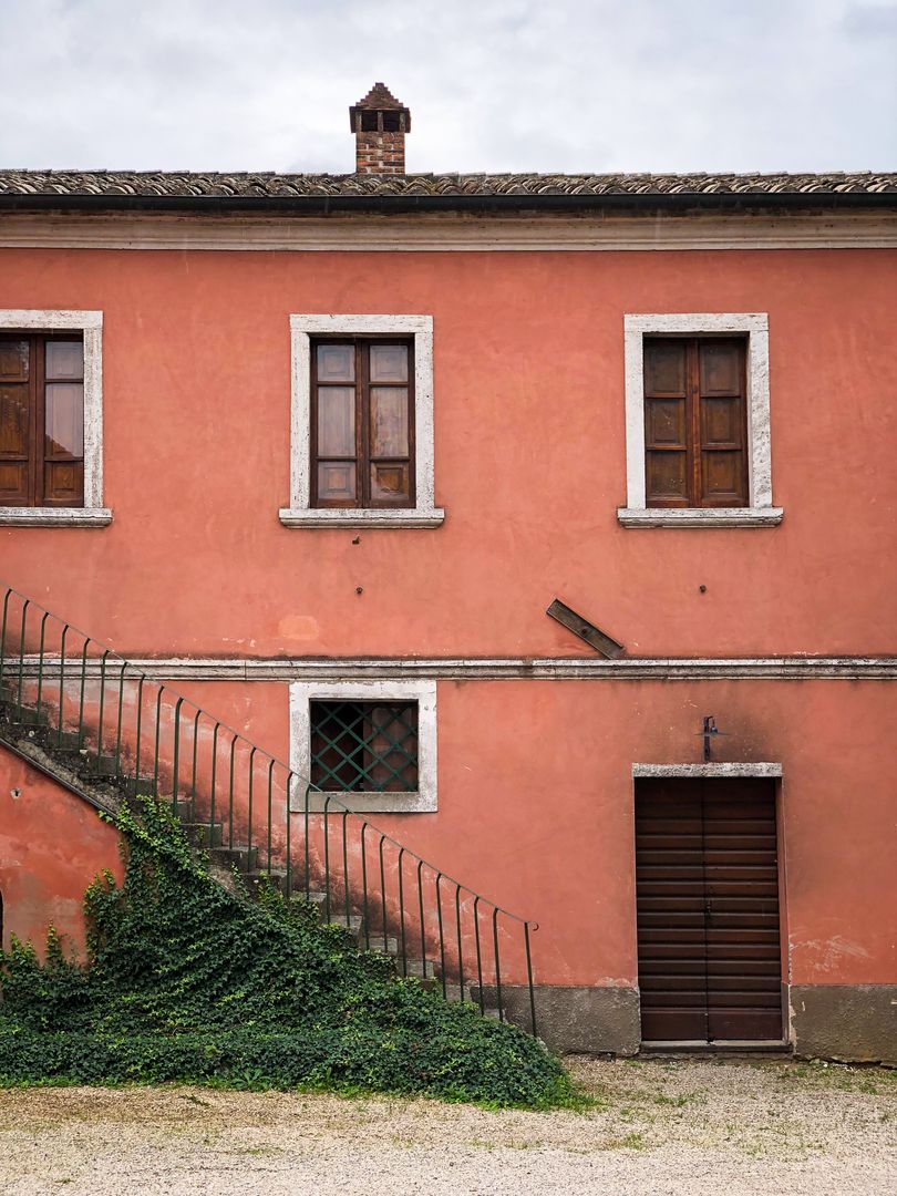 Rustic Pink Tuscan Facade with Ivy-Covered Staircase, Wooden Shutters and Brick Chimney