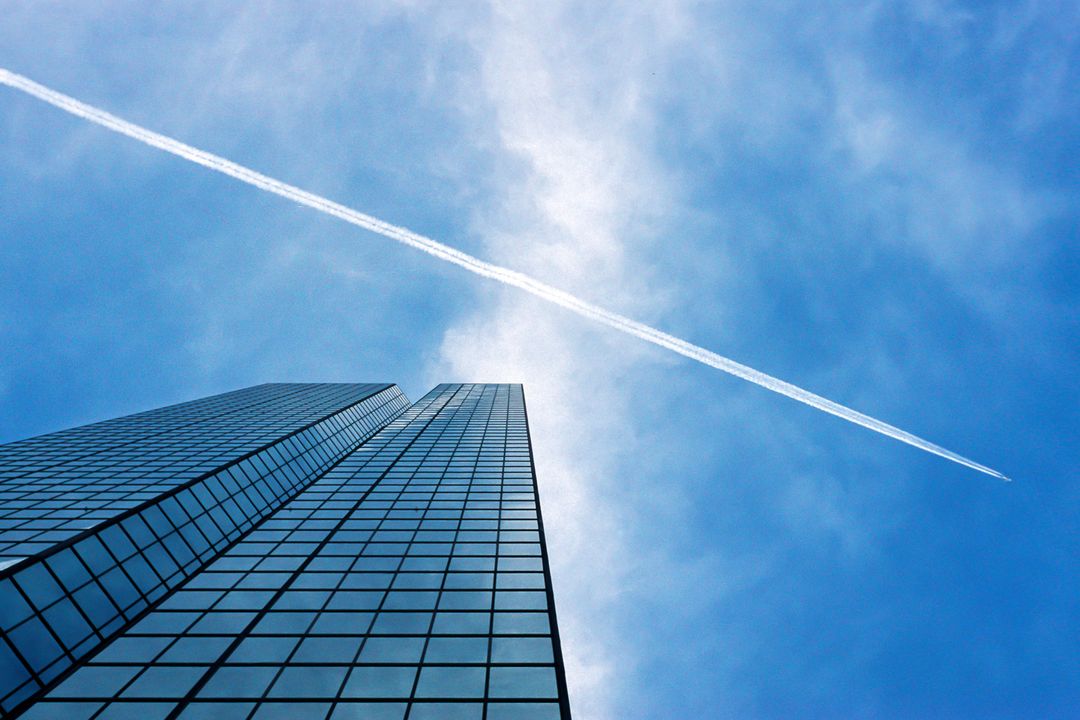 Contrail Over Skyscraper With Reflection on Glass Windows - Free Images, Stock Photos and Pictures on Pikwizard.com