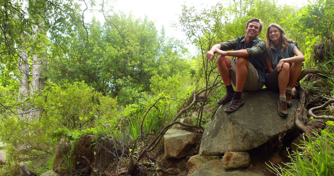 Happy Couple Relaxing on Rock During Forest Hike with Copy Space