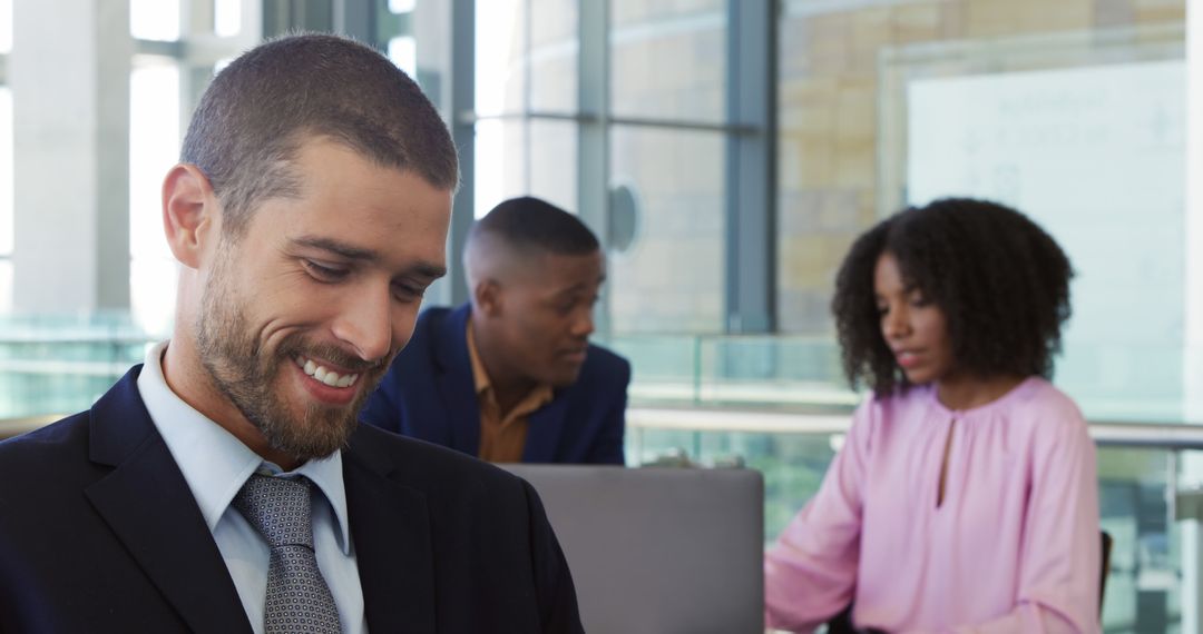 Smiling Businessman in Office with Colleagues in Background - Free Images, Stock Photos and Pictures on Pikwizard.com