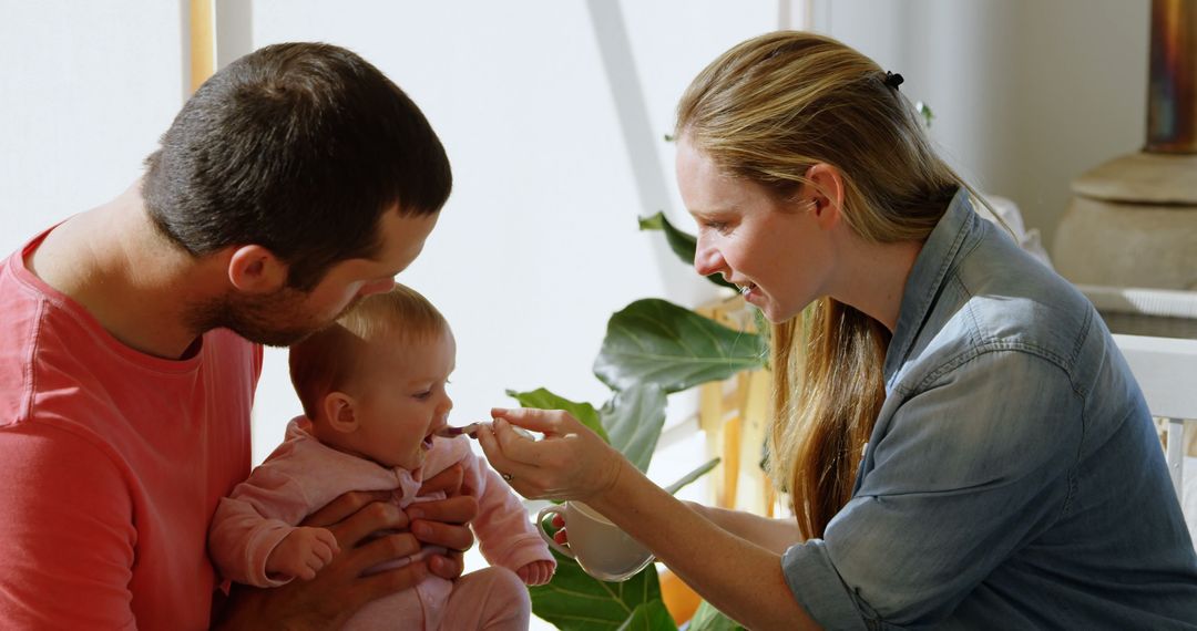 Young Parents Feeding Baby Together at Home - Free Images, Stock Photos and Pictures on Pikwizard.com