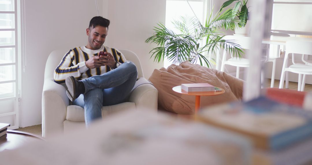 Happy Man Seated in Creative Office Chatting on Smartphone