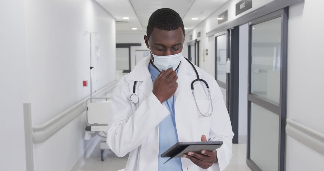 African American Doctor Using Tablet in Hospital Corridor - Free Images, Stock Photos and Pictures on Pikwizard.com