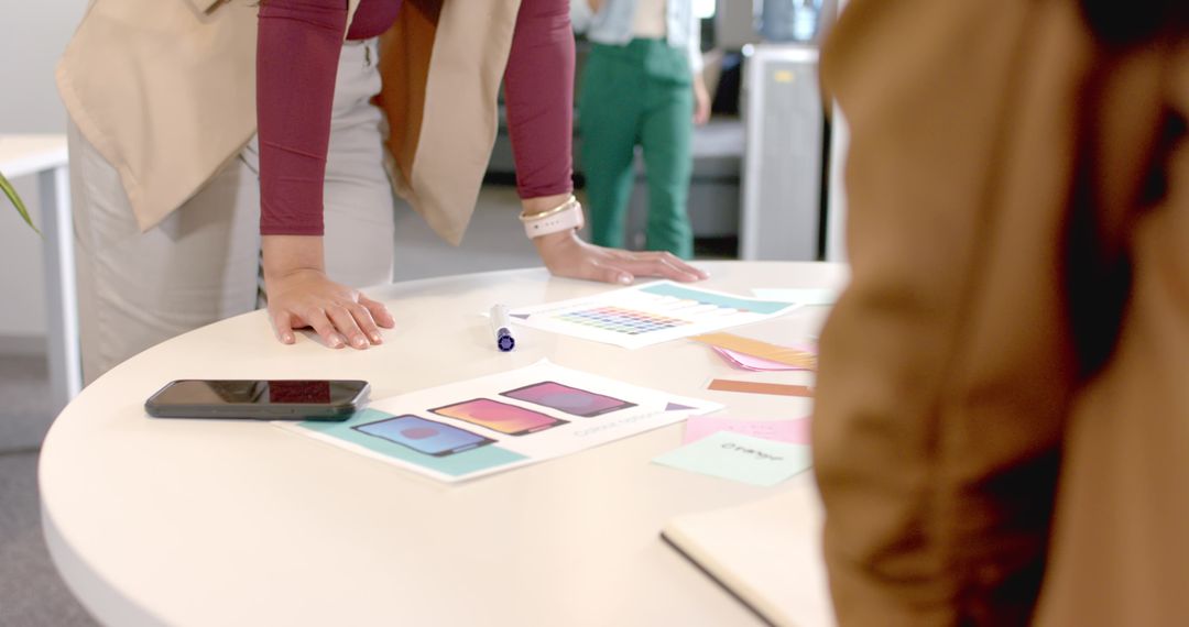 Coworkers Collaborating Over App Design Mockups in Office Meeting
