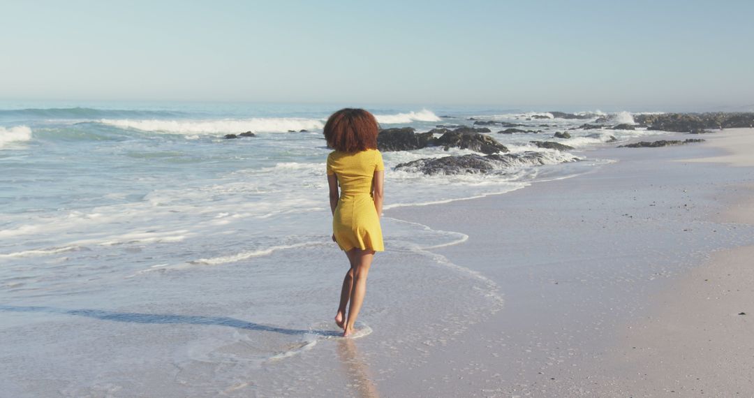 Woman Walking on Beach in Yellow Dress by Ocean Waves - Free Images, Stock Photos and Pictures on Pikwizard.com