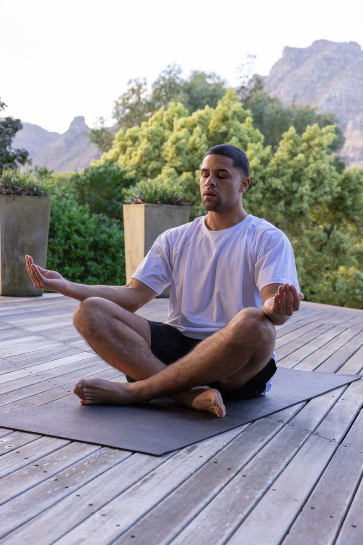 Man Meditating on Wooden Deck Surrounded by Nature