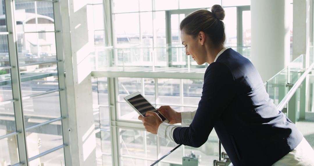 Businesswoman Using Tablet at Modern Office with Glass Wall - Free Images, Stock Photos and Pictures on Pikwizard.com