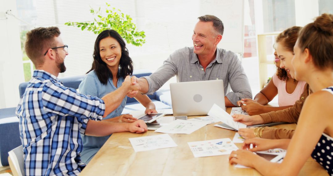 Team Members Smiling and Shaking Hands During Meeting - Free Images, Stock Photos and Pictures on Pikwizard.com