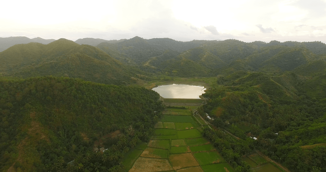 Transparent Lake Among Verdant Mountains and Fields at Sunrise