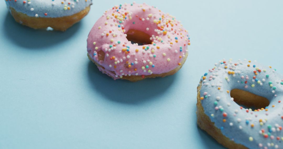 Colorful Frosted Doughnuts with Sprinkles on Light Blue Background - Free Images, Stock Photos and Pictures on Pikwizard.com