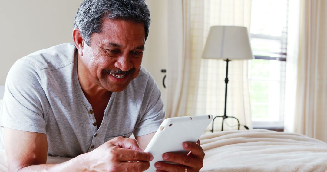 Mature Hispanic man using digital tablet at home - Free Images, Stock Photos and Pictures on Pikwizard.com