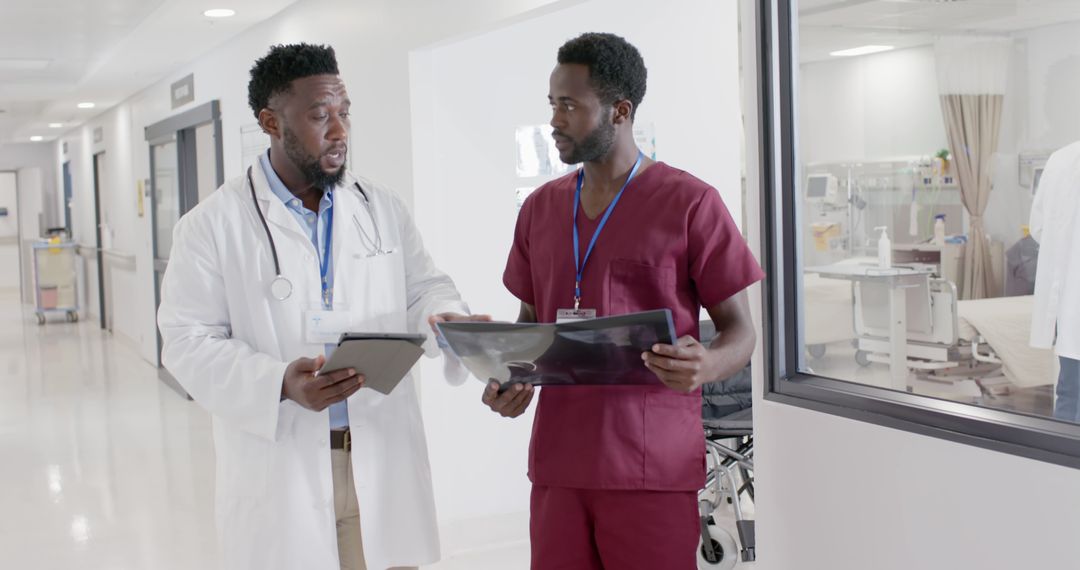 African American Doctors Discussing Medical Results in Hospital Corridor - Free Images, Stock Photos and Pictures on Pikwizard.com