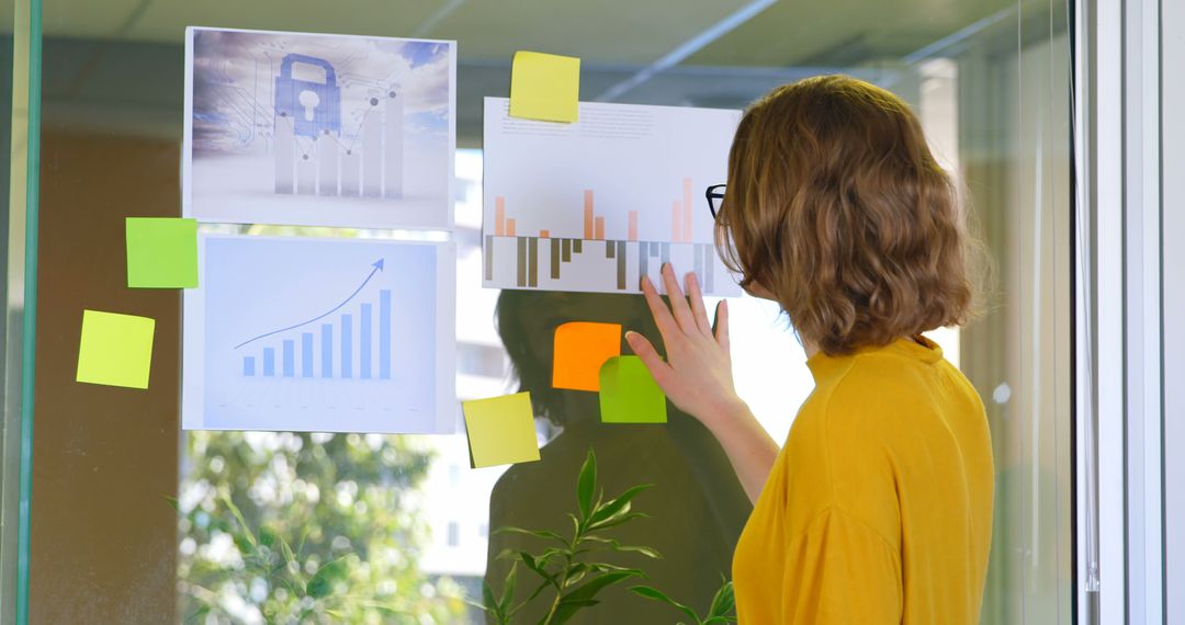 Businesswoman Analyzing Data Charts on Glass Wall in Office - Free Images, Stock Photos and Pictures on Pikwizard.com