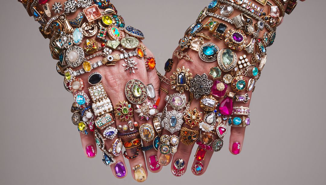 Hands Wearing Stacked Gemstone Rings and Layered Bracelets with Colorful Nail Art
