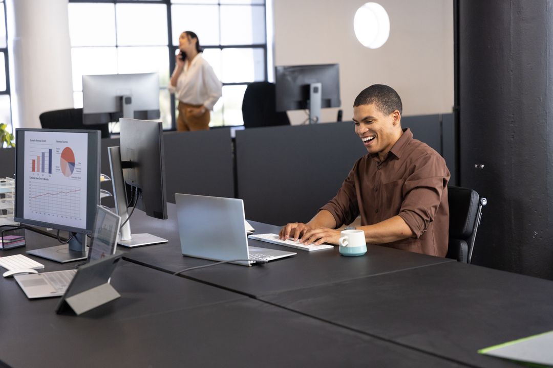 Smiling Professional Typing at Desk in Contemporary Office