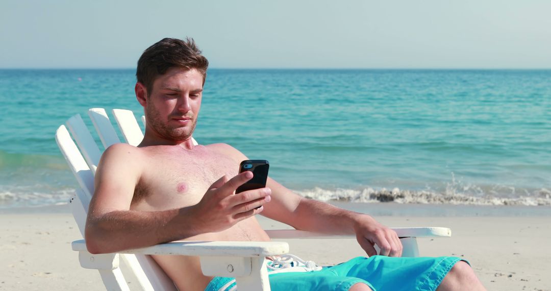 Young Man Relaxing on Beach Chair Using Smartphone - Free Images, Stock Photos and Pictures on Pikwizard.com