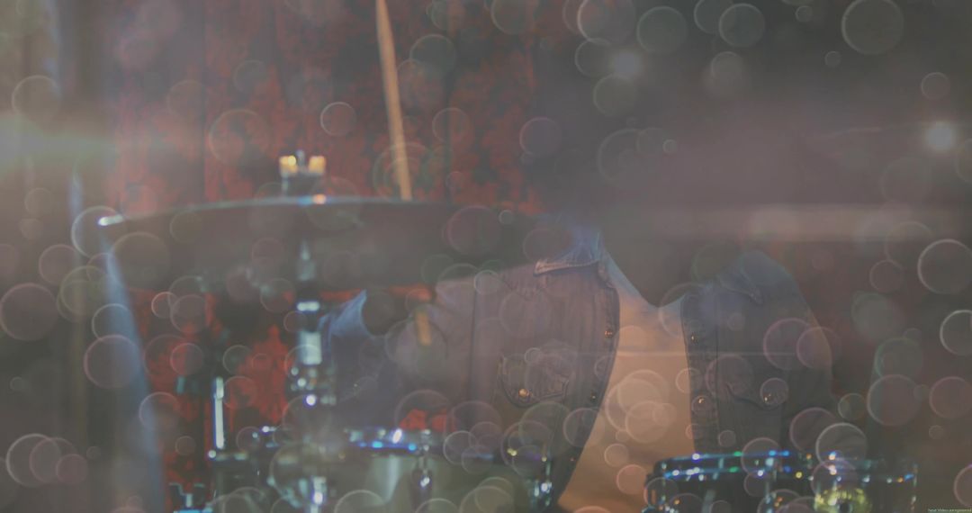 Denim-Clad Drummer Playing Drums in Artistic Room with Floating Bokeh